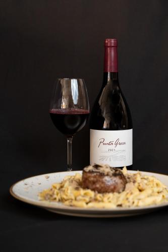 a glass of red wine next to a plate of food at Hotel Marina in Fažana