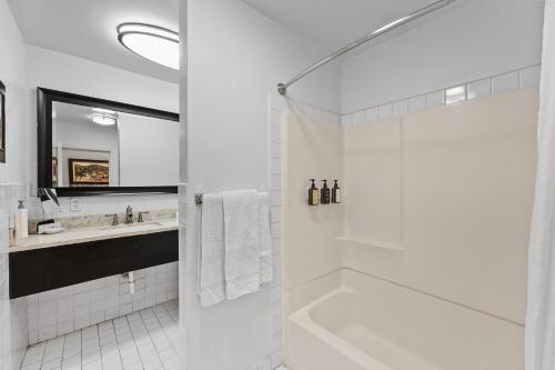 a white bathroom with a tub and a sink at Catalina Courtyard Suites in Avalon