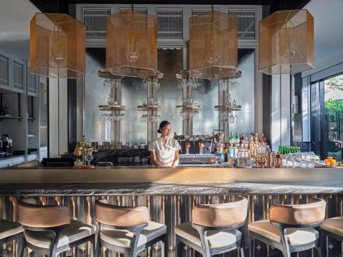 a woman standing behind a bar in a restaurant at InterContinental Chiang Mai The Mae Ping in Chiang Mai