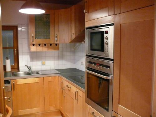 a kitchen with wooden cabinets and a microwave at Apartments Seegartl in Fuschl am See