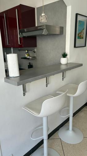 - une cuisine avec 2 chaises blanches et un comptoir dans l'établissement Nice Séjour Detente Studio Lumineux Balcon Cuisine Equipée Wifi, à Nice