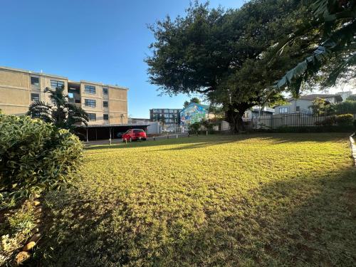 a green park with a tree and a red car at Beautiful Apartment In Morningside in Vosburg