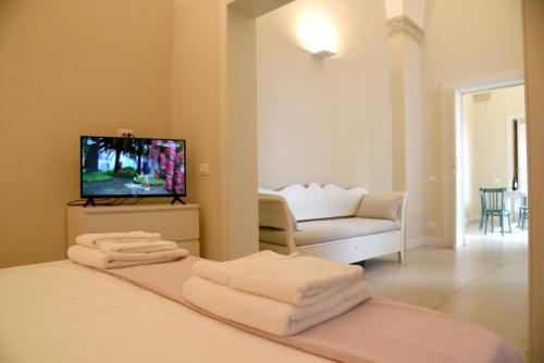 une chambre avec un lit avec une télévision et un canapé dans l'établissement Palazzo Rudiae - Sant'Irene, à Lecce