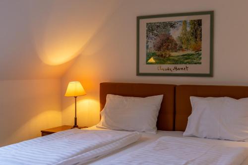 a bed with white sheets and a picture on the wall at Friskó Panzió in Zalakaros