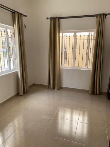 an empty room with two windows and curtains at Maison de Pagoda in Port Louis