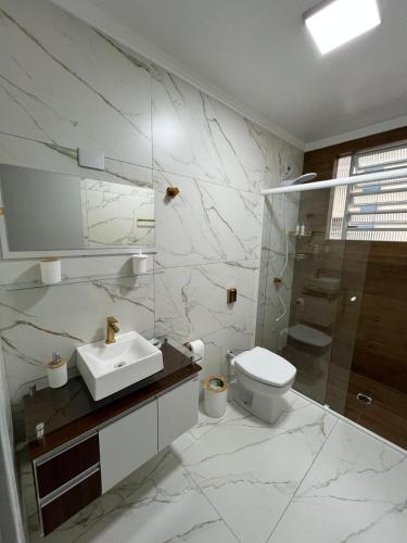 a white bathroom with a sink and a toilet at Aconchegante apto no Centro! in Concordia