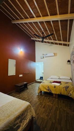 a bedroom with two beds and a wooden floor at Prajwal home stay in Hampi