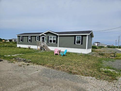 una pequeña casa con dos sillas delante en Full Bedroom, en Glace Bay