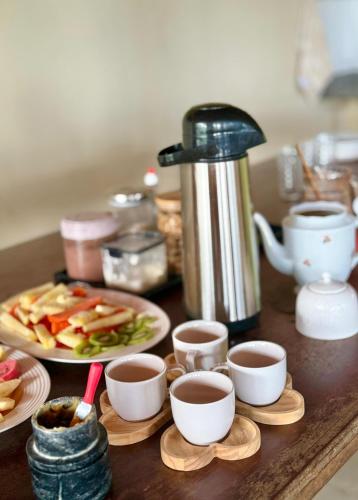 a table with plates of food and cups of tea at Pousada Viva Praia in Paracuru