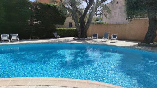 une grande piscine bleue avec des chaises et un arbre dans l'établissement Joli studio Cap d'Antibes, à Antibes