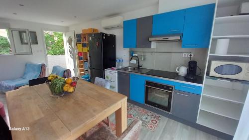 une cuisine avec des placards bleus et une table avec des fruits. dans l'établissement Duplex cosy, 100m plage Argelès, à Argelès-sur-Mer