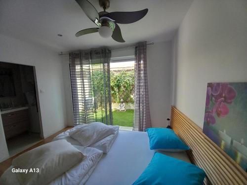 une chambre avec un lit avec un ventilateur et une fenêtre dans l'établissement Duplex cosy, 100m plage Argelès, à Argelès-sur-Mer