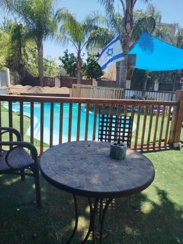 a patio table with an umbrella next to a pool at Aloha House in Gan Shemuʼel