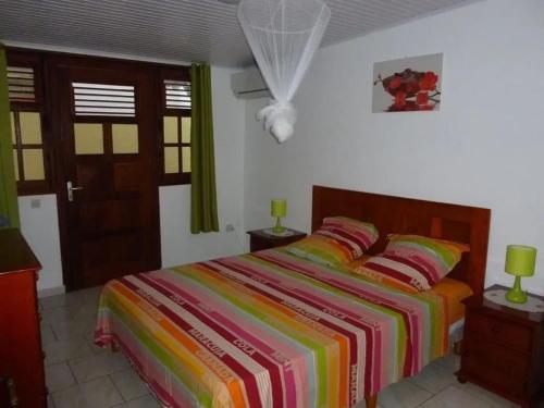 a bedroom with a bed with a colorful striped bedspread at Appartement familial à Saint-Esprit, 95m² avec terrasse in Quartier Palmène