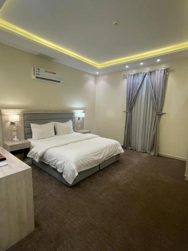 a bedroom with a large white bed and a window at الابنوس للشقق الفندقية in Abha