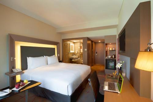 a hotel room with a large bed and a desk at Novotel Chennai OMR in Chennai