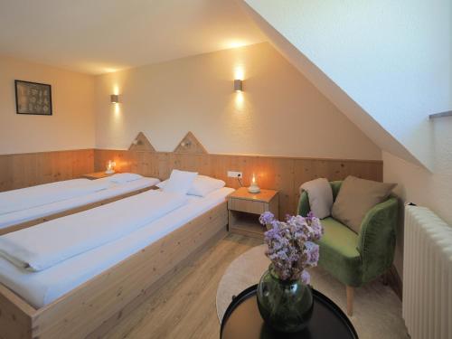 a bedroom with a large bed and a green chair at Landhotel Waldheim in Pliezhausen