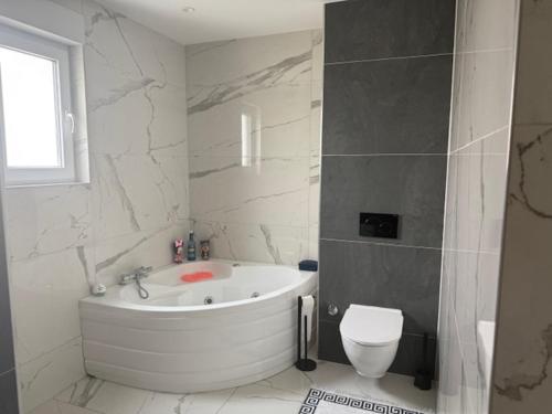 a white bathroom with a tub and a toilet at Villa in Ingersheim