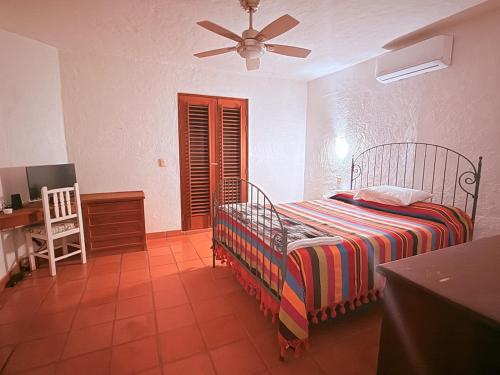 a bedroom with a bed and a desk with a fan at Casa Basea in Zihuatanejo