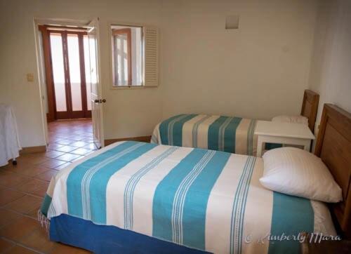 a bedroom with two twin beds and a doorway at Casa Basea in Zihuatanejo