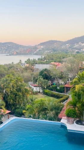 a resort swimming pool with a view of the water at Casa Basea in Zihuatanejo