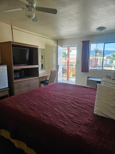 a bedroom with a large bed with a red bedspread at Camaray Motel in Oroville