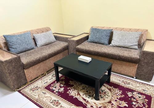 a living room with two couches and a coffee table at Jawharet Al Kheir Furnished Apartments in Salalah