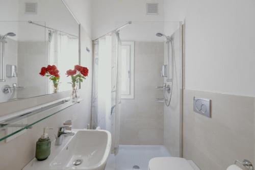 Un baño blanco con lavabo y espejo. en 24 Duomo - Camera centralissima, en Florencia