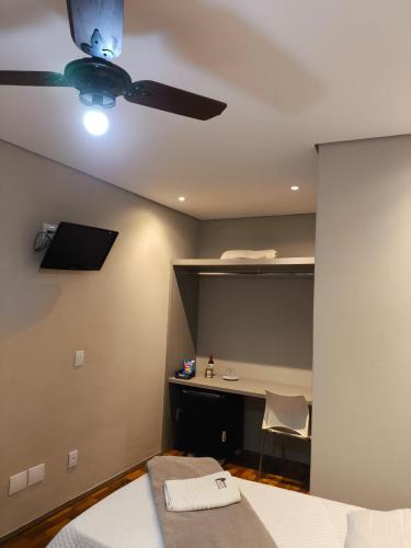 a bedroom with a ceiling fan and a bed and a desk at Café Palace Hotel in Três Pontas