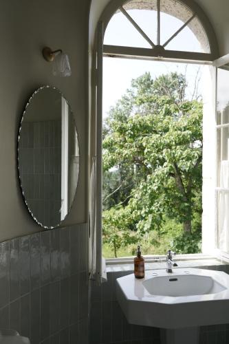 un bagno con specchio, lavandino e finestra di Chateau de Pomiro chambres d'hôtes et gîte a Montréal