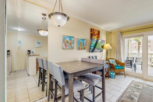 a dining room with a wooden table and chairs at Victorian Condos Barefoot Beach Haven in Galveston