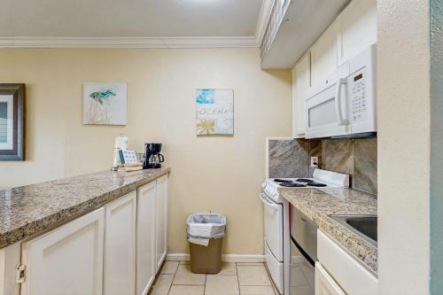 a kitchen with white cabinets and a sink at Victorian Condos Barefoot Beach Haven in Galveston