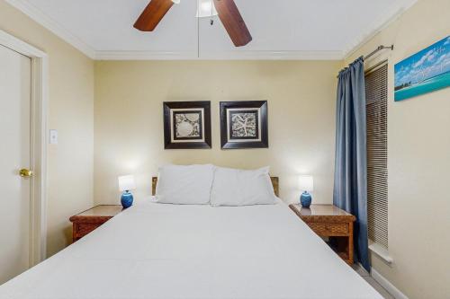 a bedroom with a large white bed with two lamps at Victorian Condos Barefoot Beach Haven in Galveston