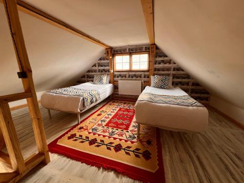 a attic room with two beds and a rug at Hnameni Bovadzor Lodge in Maksim Gorʼkiy