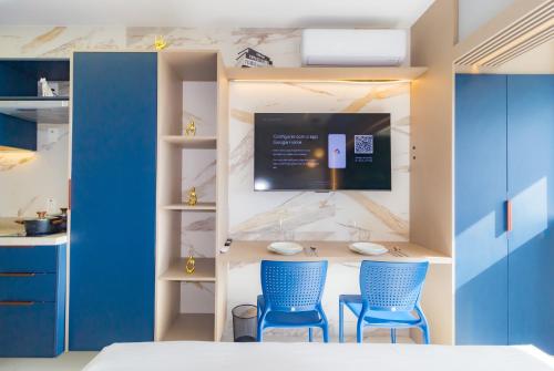 a room with two blue chairs and a table with a tv at Prime Grand Vitrali Moema in Sao Paulo