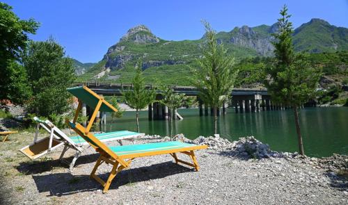 two chairs and a bench next to a lake at Kulla e Vjeter (Bar Restaurant, Guesthouse, Parking and Camping) in Koman