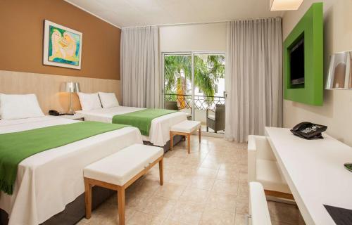 a hotel room with two beds and a balcony at NH Haiti El Rancho in Port-au-Prince