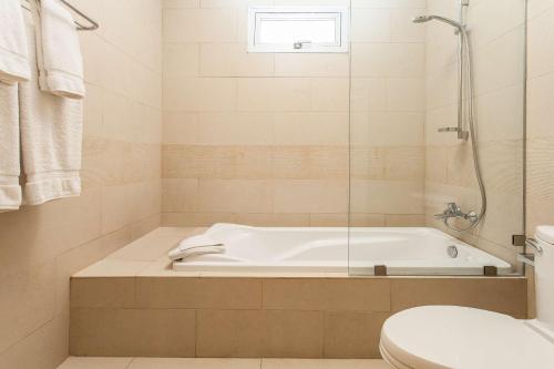 a white bathroom with a tub and a toilet at NH Haiti El Rancho in Port-au-Prince