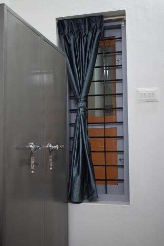 a window with a curtain next to a door at FlexTays Campus - Budget Student Stays in Trivandrum