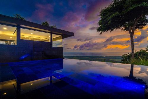 une maison avec un reflet dans l'eau au crépuscule dans l'établissement New Luxury! Panoramic Views-pool-private-gated, à Portalón