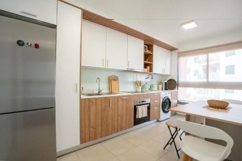 a kitchen with white cabinets and a table at Hygge Madeira by LovelyStay in Caniço