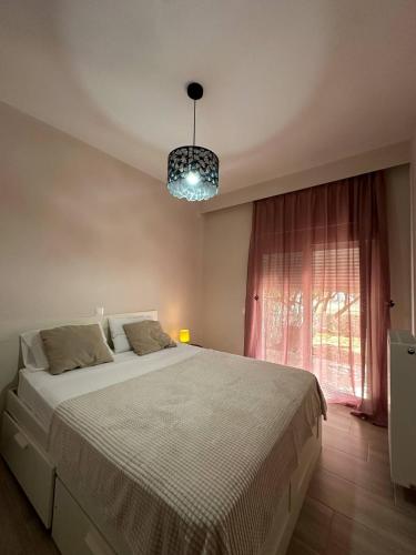 a bedroom with a large bed and a chandelier at Ledjon apartament in Artemida