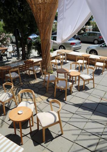 a group of wooden chairs and tables and a tree at Hotel Brilant in Shëngjin