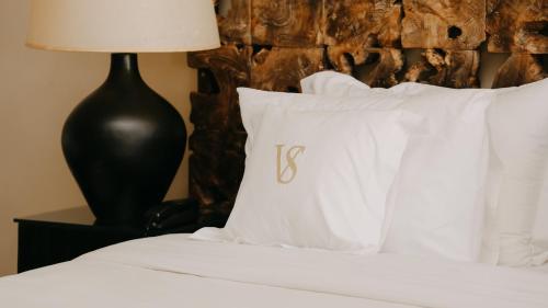 a bed with white pillows and a black lamp at Villa Soraya Lodge & Spa in Rabat