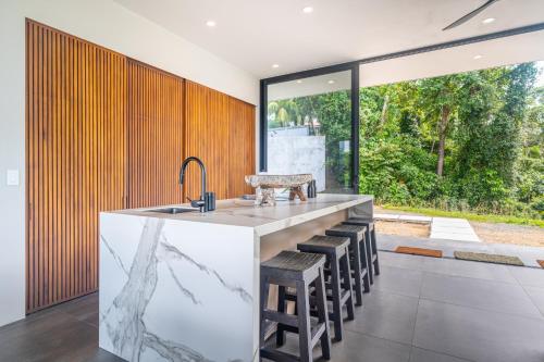 a kitchen with a sink and a counter with stools at New! Modern-luxury-3 Suites-pool-ojochal-100mbps in Ojochal