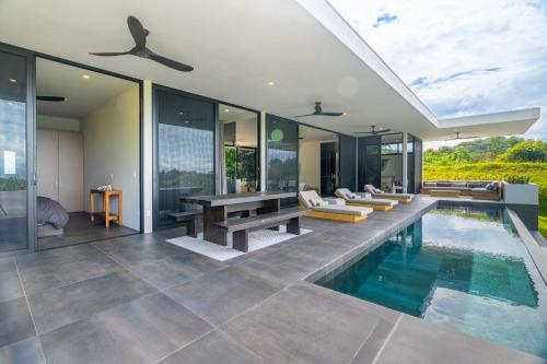 a villa with a pool and a table and benches at New! Modern-luxury-3 Suites-pool-ojochal-100mbps in Ojochal