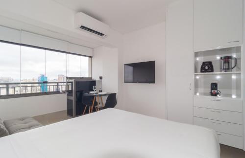 a white bedroom with a bed and a tv at Prime Grand Vitrali Moema in Sao Paulo