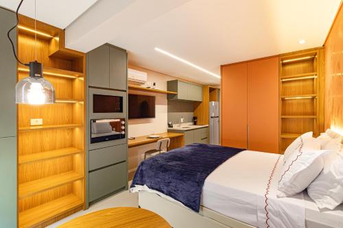 a bedroom with a bed and a kitchen with cabinets at Prime Grand Vitrali Moema in Sao Paulo