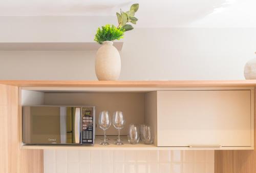 a shelf with a microwave and wine glasses on it at Prime Grand Vitrali Moema in Sao Paulo