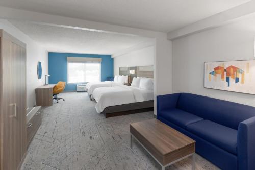 a hotel room with a bed and a blue couch at Holiday Inn Express Hotel & Suites Huntsville West - Research Park by IHG in Huntsville